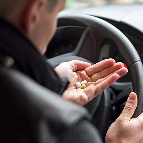 Male driver with medication in-hand - find out how ADHD and car accidents interact
