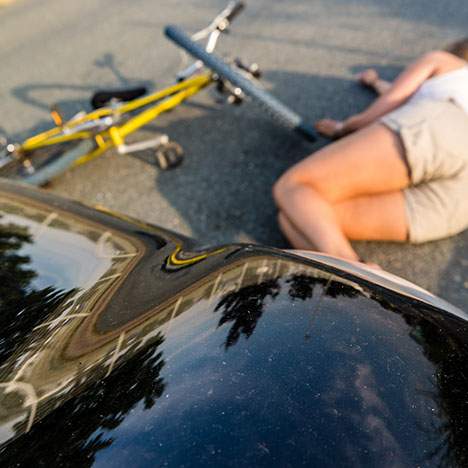 A woman lies on the ground after a bike accident.