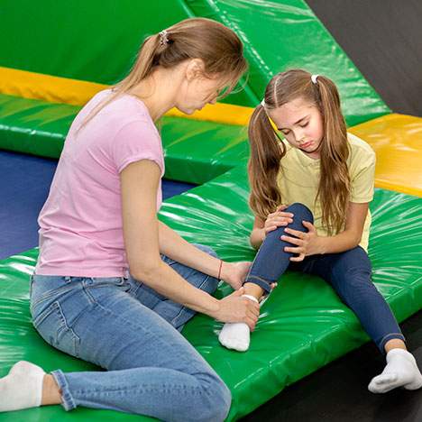 An adult comforts a child after injury at a trampoline park.