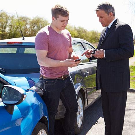 Two motorists discuss insurance information after a car accident.