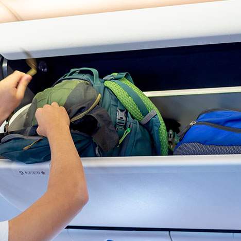 A passenger places luggage in the overhead compartment pre-flight.