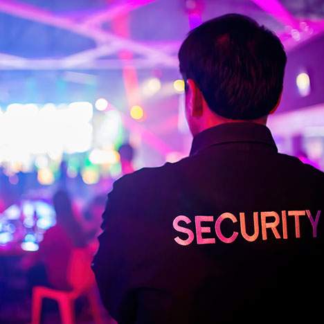 A security guard observes the nightclub dance floor to keep patrons safe.