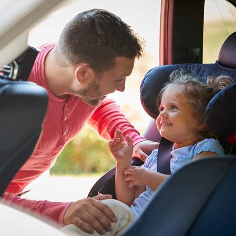 Father securing child in car seat, in case the scenario "my child was in a car accident" occurs