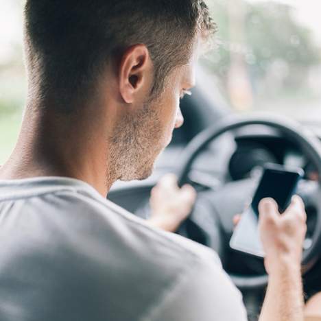 Distracted driver looking at his phone, at risk of getting negligent operator points on his record