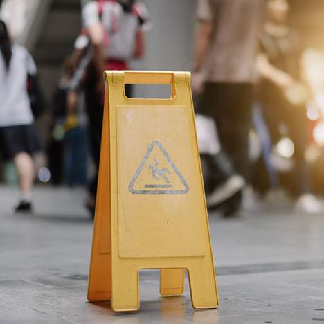 Sign cautioning slippery surface among a crowd, suggesting need for a slip and fall injury attorney