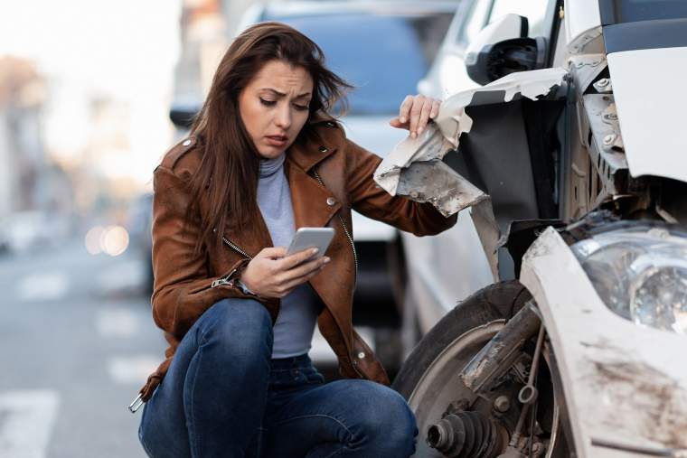 A distressed woman on her phone after getting in a car accident