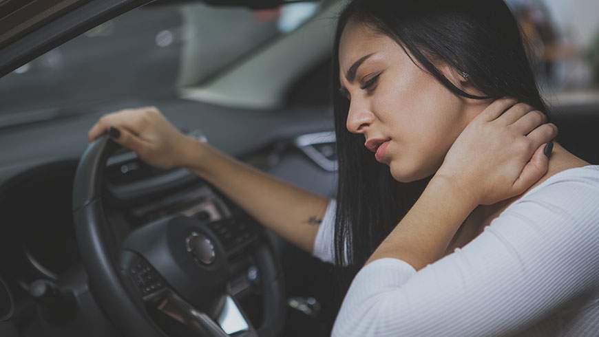 Woman rubs her back and neck after sustaining injury in car accident