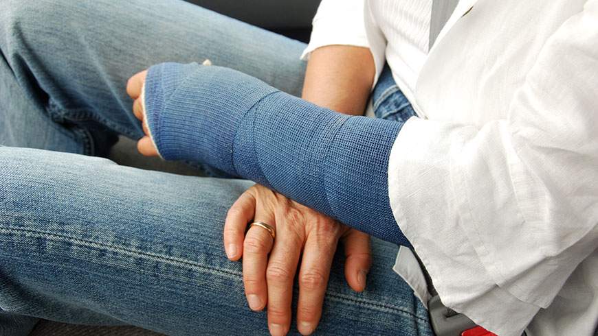 Woman sits with her arm in cast after injury in an auto accident