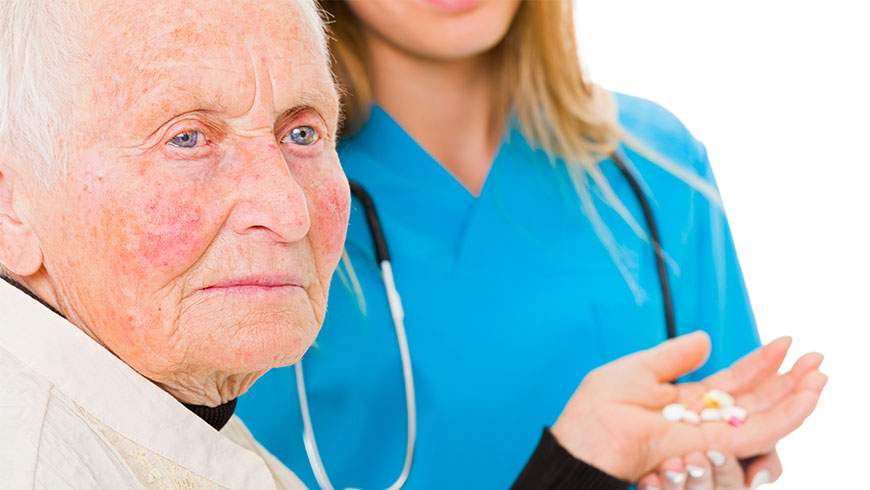 An older woman looks sad as she takes her daily prescriptions in a nursing home