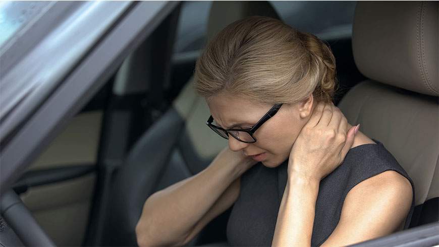 A woman rubs her neck after suffering a possible whiplash injury after an auto collision