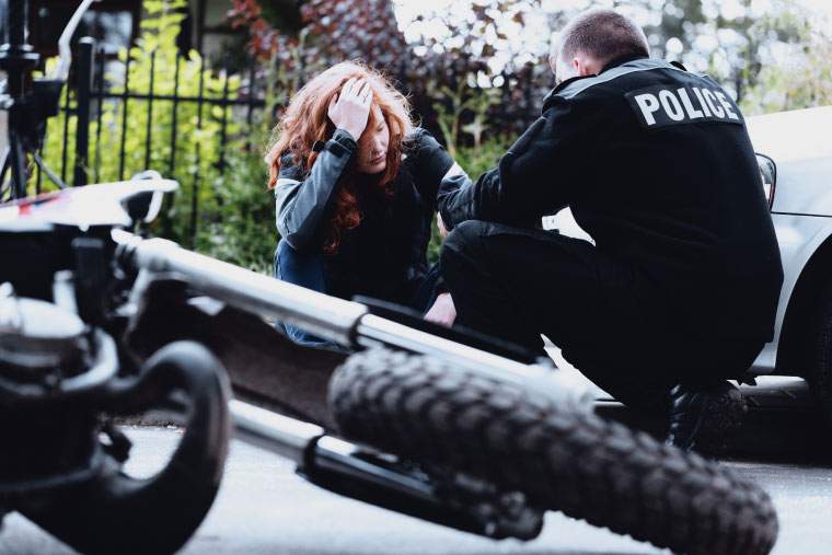 A distraught woman consulting with police after a motorcycle accident
