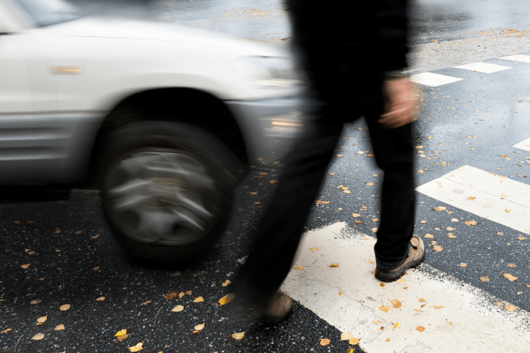 A pedestrian in a crosswalk about to be hit by a car