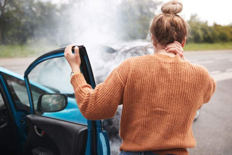 A woman standing by her car after an auto accident