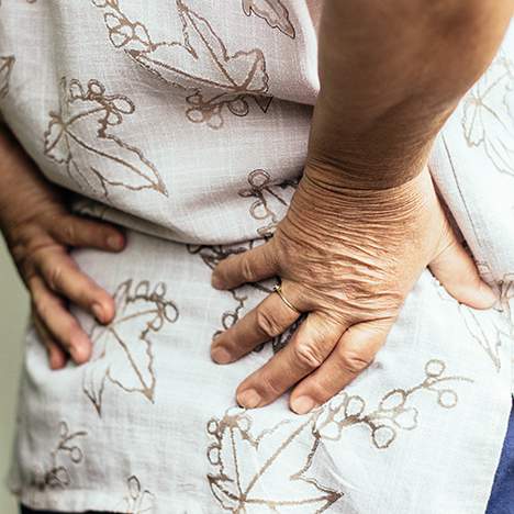 Older person clutching back in pain, answering the question can a car accident cause sciatica pain
