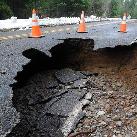 Crumbling road by traffic cones - can Biden's infrastructure plan stem bad car accidents?