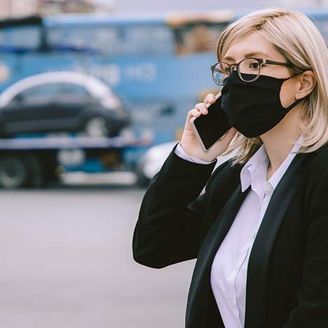 Masked woman on phone with car on tow truck in the background - why do car crashes happen?