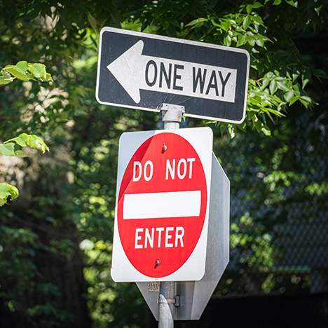 Traffic sign post with 'One Way' and 'Do Not Enter' signs, intended to prevent a wrong way crash