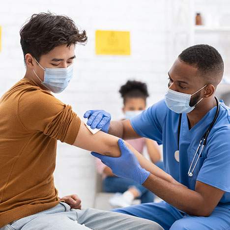 Masked individual receiving shot, potentially due to a COVID vaccine mandate