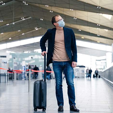 Man with surgical mask standing with luggage at airport - can you sue an airport?
