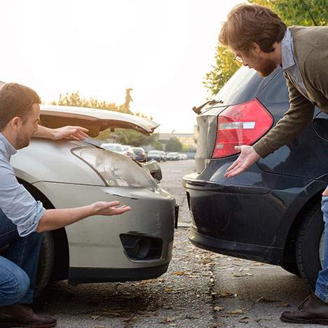 Two men examining fender bender damage - how many traffic accidents occur each year in California?