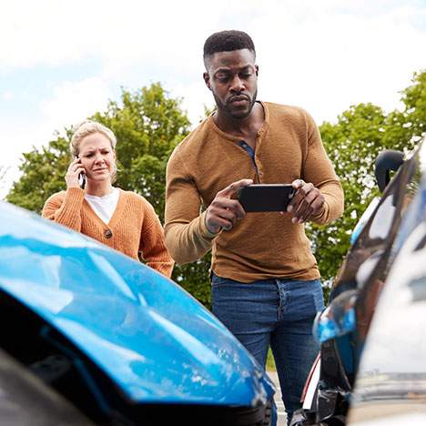 Two people taking picture of accident - why are vehicle crashes surging in 2022?