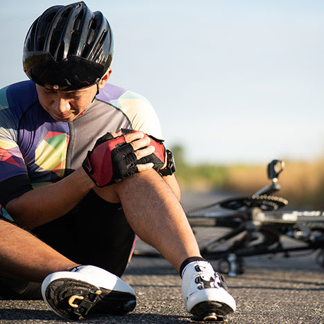 Man holding knee in pain next to bike - what are the most common causes of bicycle accidents?