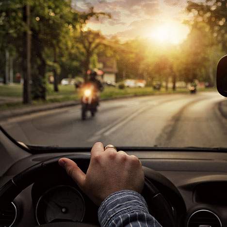 Hands on a steering wheel ahead of a motorcycle - does a car accident affect motorcycle insurance?