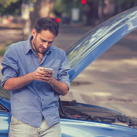 Man looking at a phone after car crash, perhaps wondering: 'Can I sue the city for a car accident?'