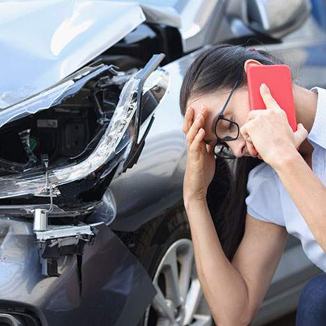 Woman holding head on phone next to a wreck potentially caused in a Fontana car accident