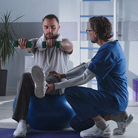 Man working with physical trainer - who pays for physical therapy after car accident injuries?