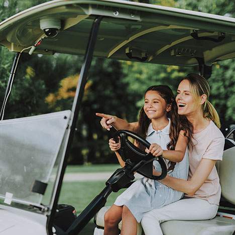 Mother with daughter smiling in golf cart - when should you consider a golf cart injury lawsuit?