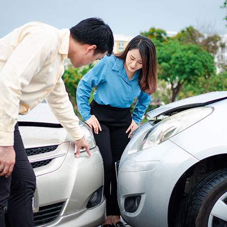 two cars hit bumpers, man and woman looking at the damage - What Can You Sue for in a Car Accident