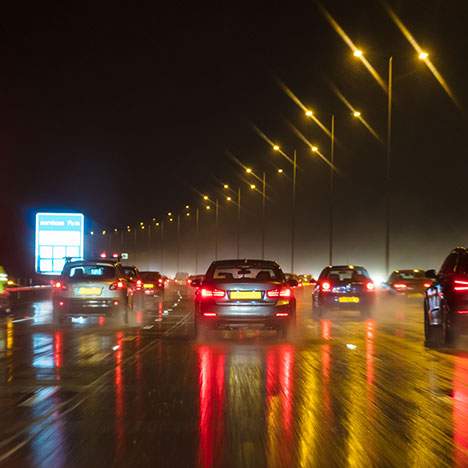 highway at night with cars and wet pavement - car accidents caused by rain