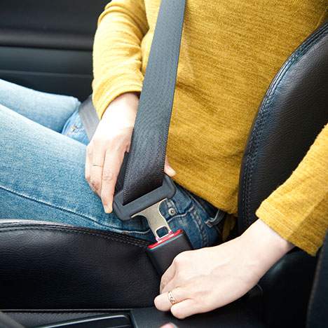 driver putting on seatbelt to reduce injuries