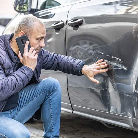 man on phone with viable damage to vehicle